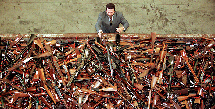 An official with Australia’s New South Wales Police looks at a pile of about 4,500 banned firearms in Sydney that had been handed over in a buy-back scheme in 1996.