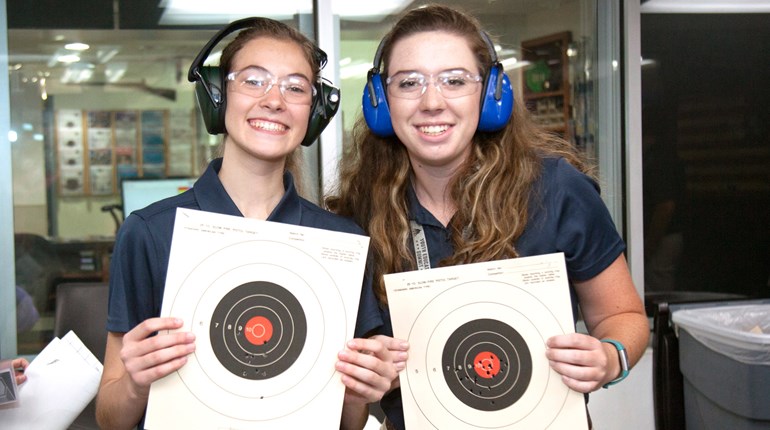 2 girls holding paper targets